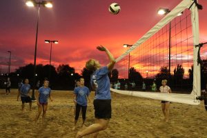 KC Crew league members playing sand volleyball at sunset