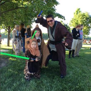 A family dressed in jedi robes and a child as an ewok with toy lightsabers at Berkley Riverfront